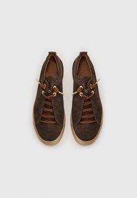 Brown suede sneakers with a rounded toe, gold-tone lace holes, and brown elastic laces. Textured sole for grip and durability.