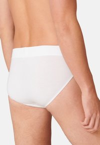 Slip bianchi in cotone con una texture liscia, una morbida fascia elastica in vita e una vestibilità aderente, che evidenzia un design minimalista.