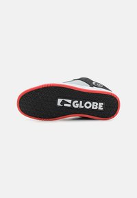 Juoda ir raudona guminė sportbačių padas, pasižymintis tekstūriniu sukibimo raštu su 'GLOBE' logotipu. Lygus pilkas viršus su juodais akcentais.