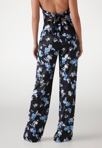 Pantaloni cu talie înaltă, cu croi larg, din țesătură neagră, cu imprimeuri florale albastre și albe, având detalii cu legare la spate.