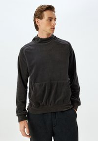 Fleecetröja i mörkgrått, med hög krage, framficka och ribbade ärmslut. Texturerad tyg med en avslappnad passform.