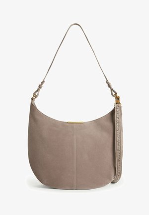 Borsa a spalla in pelle scamosciata morbida color taupe con ferrature dorate, forma curva, tracolla regolabile e tracolla decorativa staccabile con testo in rilievo.