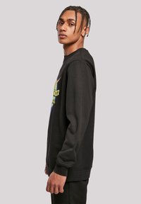 Melna sporta jaka ar daudzkrāsainu grafisku dizainu priekšpusē. Garas piedurknes ar ribotām aprocēm un apaļu kakla izgriezumu. Brīva piegriezuma stils.