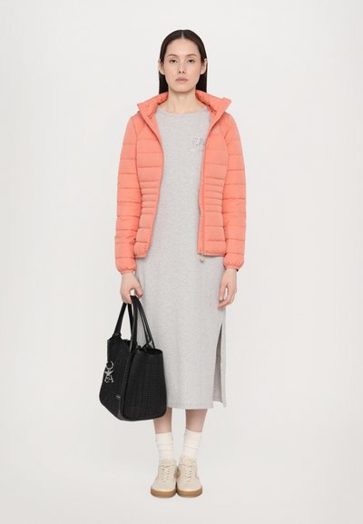 Giubbotto puffer corallo con design trapuntato, vestito grigio di lunghezza media, borsa a tracolla nera intrecciata e sneaker chiare con dettagli color beige.