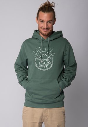 Green cotton hoodie with a front pocket, drawstring hood, and a white mountain and tree graphic. Soft texture, casual fit.