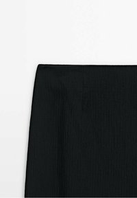 Jupe en tissu côtelé noir avec une ceinture droite, présentée sur fond blanc.
