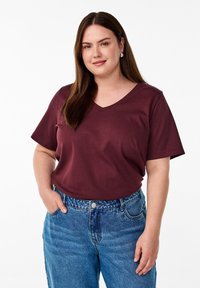 T-shirt bordeaux à col V en coton doux avec des manches courtes, associé à un jean en denim bleu clair taille haute à coupe classique.