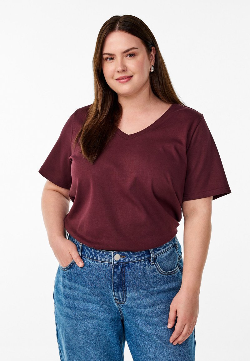 T-shirt bordeaux à col V en coton doux avec des manches courtes, associé à un jean en denim bleu clair taille haute à coupe classique.