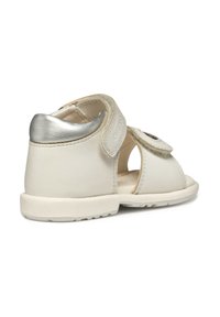 Witte leren sandaal met een metallic zilveren hakaccent, open ontwerp, klittenbandsluitingen en een gestructureerde zool voor grip en flexibiliteit.