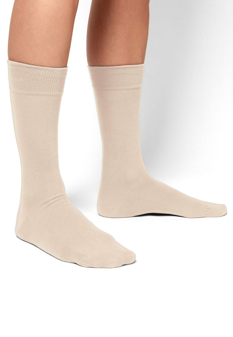 Calcetines de algodón beige con una textura suave, de longitud hasta la mitad de la pantorrilla y con puños acanalados. Diseño simple sin patrones ni acentos.