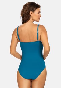 Szmaragdowy jednoczęściowy kostium kąpielowy z regulowanymi ramiączkami i gładką, matową teksturą; posiada klasyczny design z okrągłym dekoltem na plecach.