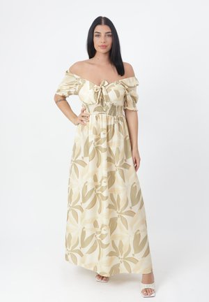 Robe maxi avec un design à épaules dénudées, buste smocké, en crème avec des motifs floraux verts. Texture lisse et silhouette fluide.