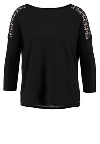 Zwarte top met driekwartmouwen, voorzien van kanten bloemenaccenten op de schouders, een relaxte pasvorm en een ronde halslijn. Zachte textuur.