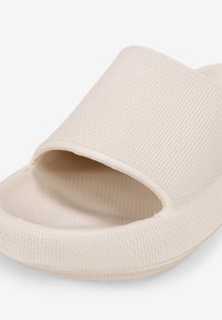 Sandale à glissière beige clair avec un dessus en caoutchouc texturé, conception ouverte au niveau des orteils et semelle rembourrée. Caractéristiques d'une finition lisse et des bords arrondis.