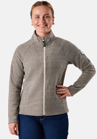 Giacca in pile taupe con zip, caratterizzata da un motivo testurizzato, colletto alto e tasche laterali. Presenta una toppa con logo sulla manica sinistra.