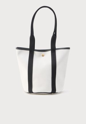 Hvid lærredsnettaske med lange sorte håndtag og en lille rund guldknap midt for.