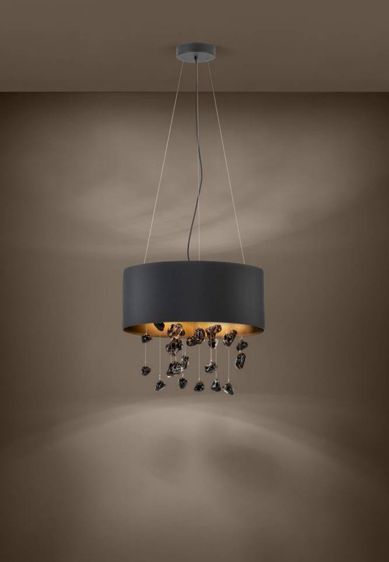 Moderne schwarze Trommel-Pendelleuchte mit hängenden dekorativen dunklen Glassteinen, die von der Decke gegen eine schlichte braune Wand hängen.