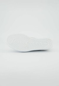 Bílá gumová podrážka tenisky s texturovaným vzorem pro lepší uchopení, s vyraženým názvem značky. Ploché provedení s zaoblenými okraji.