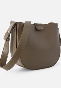 Borsa a spalla in pelle sintetica marrone con forma arrotondata, tracolla regolabile e dettaglio a pattina. Tessuto liscio con hardware minimal.