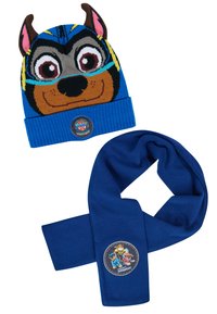 Cappello di maglia blu con faccia di animale, dotato di orecchie marroni e dettagli a righe blu. Accompagnato da una sciarpa blu uniforme con una toppa caratterizzata.
