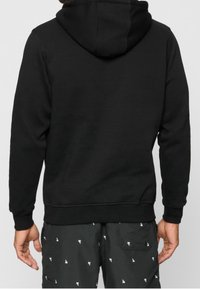 Felpa nera con cappuccio e tasca a marsupio. Realizzata in tessuto morbido, presenta polsini e vita a coste.