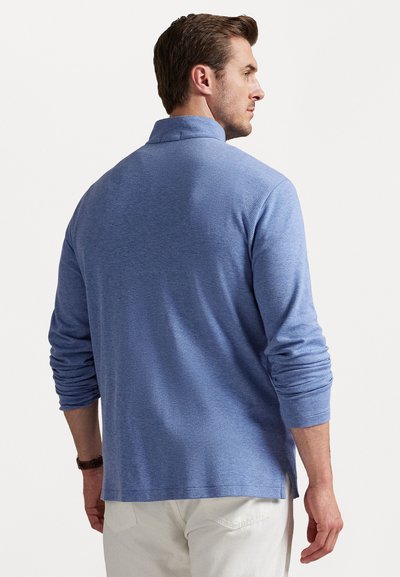 Camisa polo de manga larga azul, hecha de material suave, con un corte relajado, cuello doblado y aberturas laterales para facilitar el movimiento.