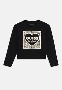 Black long-sleeve cropped shirt with a metallic leopard print square featuring a heart and "GUESS Los Angeles EST. 1981" text on the front.
