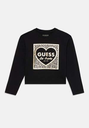 Črna dolga majica s kratkimi rokavi, krojena, z metalno leopardo vzorčasto kvadratno sliko, ki vključuje srce in napis "GUESS Los Angeles EST. 1981" na sprednji strani.