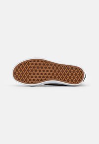 Suela de zapato con una superficie de goma marrón texturizada, que presenta un patrón de diamantes y un borde lateral blanco. Diseño plano, adecuado para el uso casual.