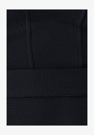 Čierna textúrovaná tkanina s vlnitým vzorom. Materiál má jemný vzhľad s viditeľnými švami a hladkým pásom.