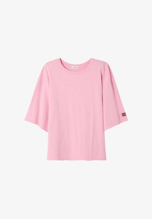 Camiseta de algodón rosa con mangas cortas y anchas y cuello redondo. Presenta el texto "AMERICAN VINTAGE" en negro en la manga.