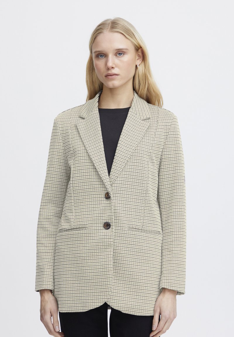 Beige ruuduline bleiser kahe esiriputusnööbiga, struktureeritud krae ja küljetaskudega. Pehme kangastekstuuri, keskmise pikkusega varrukad, kohandatud lõige.