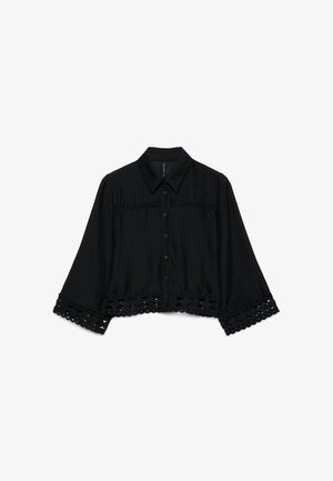 Schwarze Bluse mit langen Ärmeln, Knopfleiste vorne, weiten Ärmeln, spitzem Kragen und Spitzenverzierung an Ärmeln und Saum.