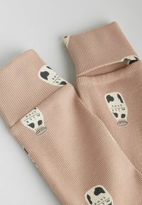 Rosa ribbad tyg med en texturerad yta; har mönster av svarta och vita mjölkflaskor på muddar. Mjukt och elastiskt design.