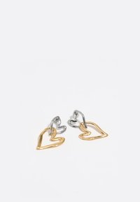 Pendientes en forma de corazón de oro y plata, con líneas entrelazadas y una textura suave, con diseños abiertos que destacan el brillo metálico.