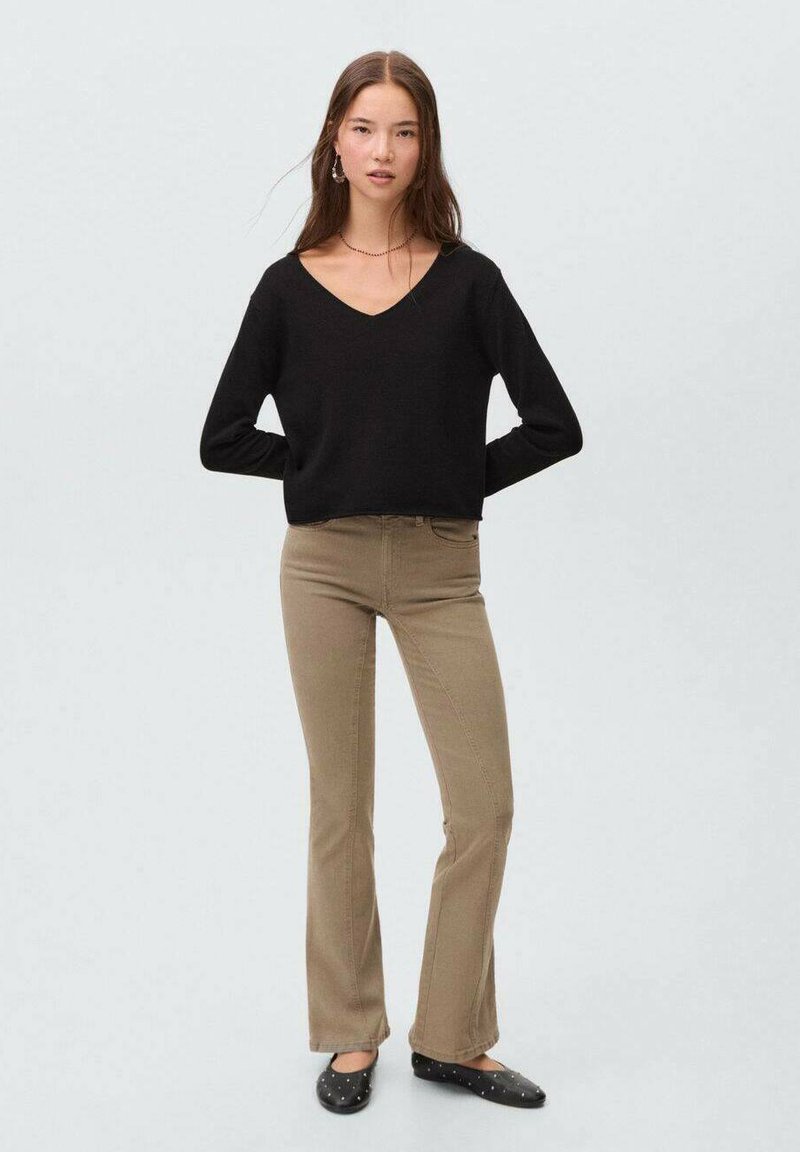 Črn pulover z V-izrezom, ohlapen kroj. Bež široke kavbojke. Črne balerinke s okrasnimi bleščicami. Preprosta zasnova z nevtralnimi barvami.