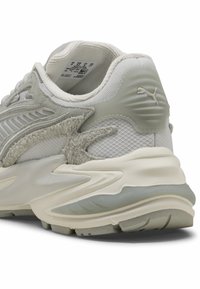 Sneaker grigio e bianco con texture in rete e suede, forma arrotondata e una suola spessa e imbottita con un accento logo discreto.