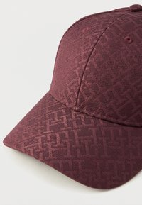 Casquette de baseball en tissu bordeaux avec un motif géométrique ton sur ton subtil, visière incurvée et œillets cousus sur les panneaux de la couronne.