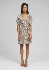 Robe portefeuille à imprimé léopard en tissu léger, avec des manches courtes, une taille ceinturée et un ourlet évasé. Couleurs beige et marron.