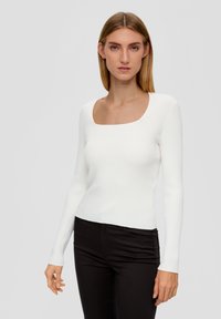Witte geribbelde lange mouwen top met een vierkante halslijn, aansluitend ontwerp en een gladde textuur, gecombineerd met zwarte broek. Eenvoudige en moderne stijl.