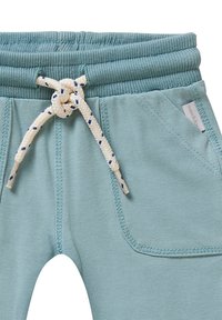 Lichtblauwe joggerpants met een gestructureerde tailleband, voorzien van een touwtouw en een zijzak met gestikte details.