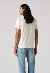 Lichtbeige t-shirt met korte mouwen, gemaakt van zachte stof, gecombineerd met lichtblauwe denim jeans, met een relaxte pasvorm en standaard snit.