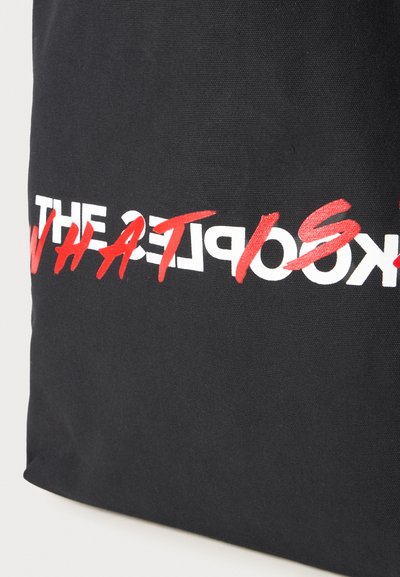 Black tote bag with bold white and red text reading “WHAT IS THE OBJECT?” displayed prominently on the front. Fabric texture is canvas.