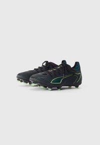 Black football cleats with a textured surface, featuring green and yellow accents, rounded toe, lace-up front, and molded studs.