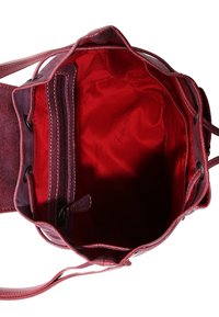 Röd läderbärkasse med mjuk textur, med en innerrficka med dragkedja, justerbart snörningsstängning och kontrasterande slät foder.
