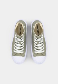 Sneaker alte in tela verde oliva con lacci bianchi, punte in gomma bianca e logo "CONVERSE" visibile all'interno.