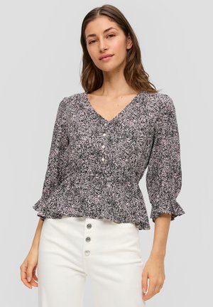 Schwarze und rosa blumengemusterte Bluse mit V-Ausschnitt, Knopfleiste und Rüschensäumen, getragen mit weißen High-Waist-Hosen.
