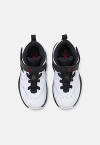 Scarpe sportive bianche con accenti neri, caratterizzate da una superficie testurizzata, lacci neri, design a metà altezza e un logo sulla fascia alla caviglia.