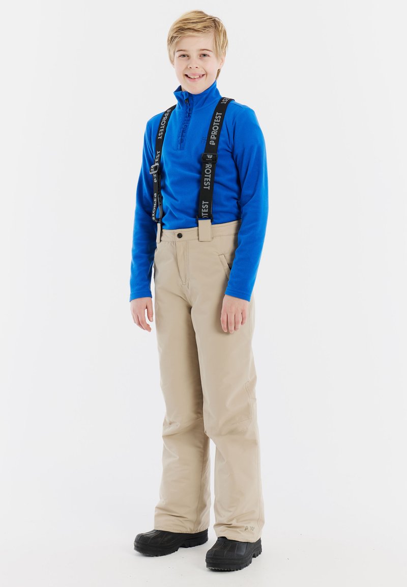 Beige skibroek met bretels, langemmouw blauw shirt en zwarte schoenen. Glad textuur en aansluitend ontwerp voor winteractiviteiten.