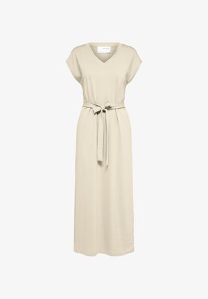 Robe beige sans manches avec un décolleté en V et une taille ceinturée. Faite en tissu doux, elle a une coupe décontractée et arrive au mollet. Sandales noires.